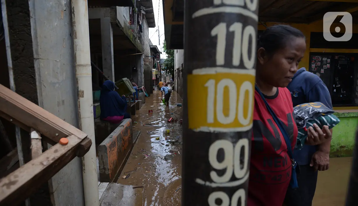 Warga membersihkan lumpur sisa banjir di Kelurahan Rawa Jati, Jakarta, Selasa (9/2/2021). Endapan lumpur yang mengendap akibat luapan Kali Ciliwung. (merdeka.com/Imam Buhori)