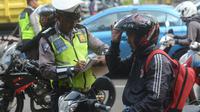 Polantas membuat surat tilang untuk pengendara motor ketika Operasi Patuh Jaya 2018 di ruas Jalan DI Panjaitan, Jakarta Timur, Jumat (27/4). Oparasi tersebut digelar untuk meningkatkan ketertiban dan kepatuhan berlalu lintas. (Merdeka.com/Imam Buhori)