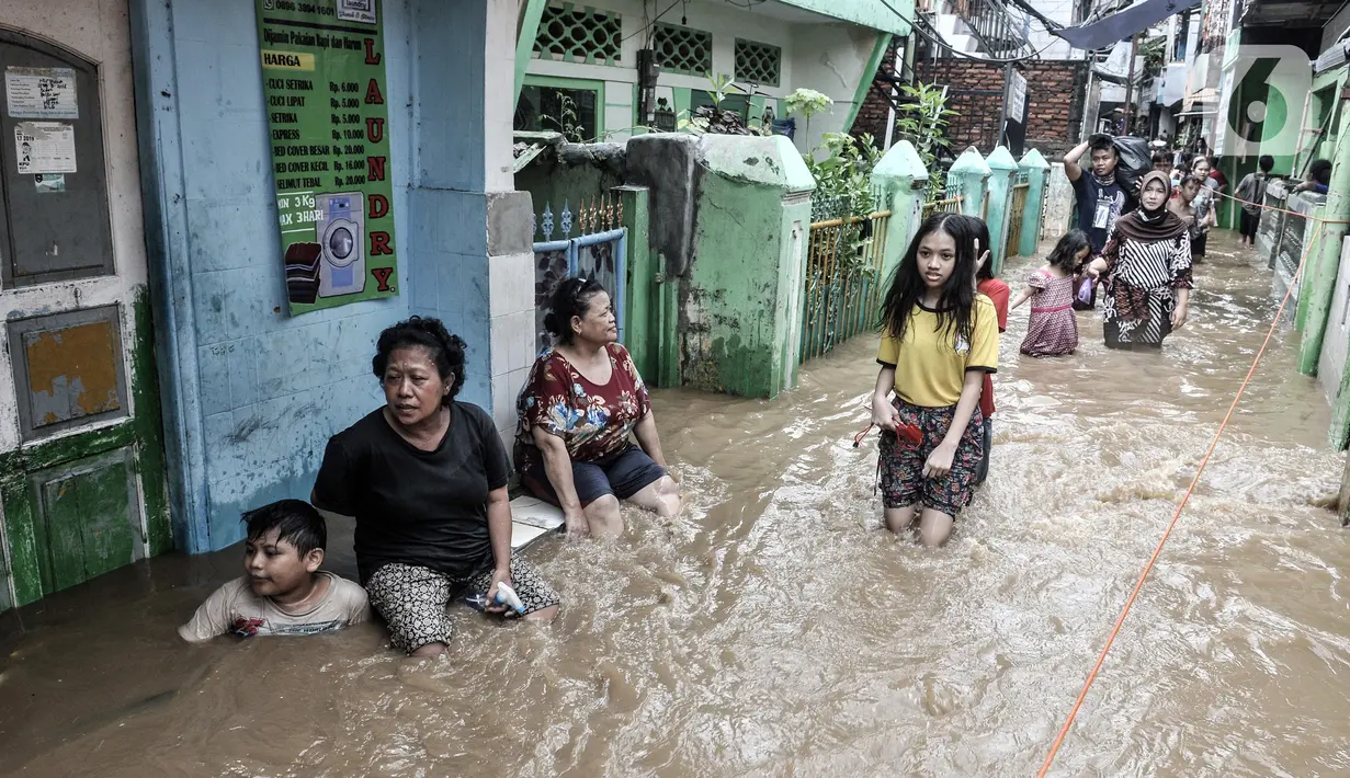 Warga menyusuri banjir yang merendam permukiman di Kebon Pala, Jakarta, Senin (8/2/2021). Banjir di Kebon Pala terus meninggi pada dini hari tadi hingga mencapai ketinggian 2,5 meter.  (merdeka.com/Iqbal S. Nugroho)