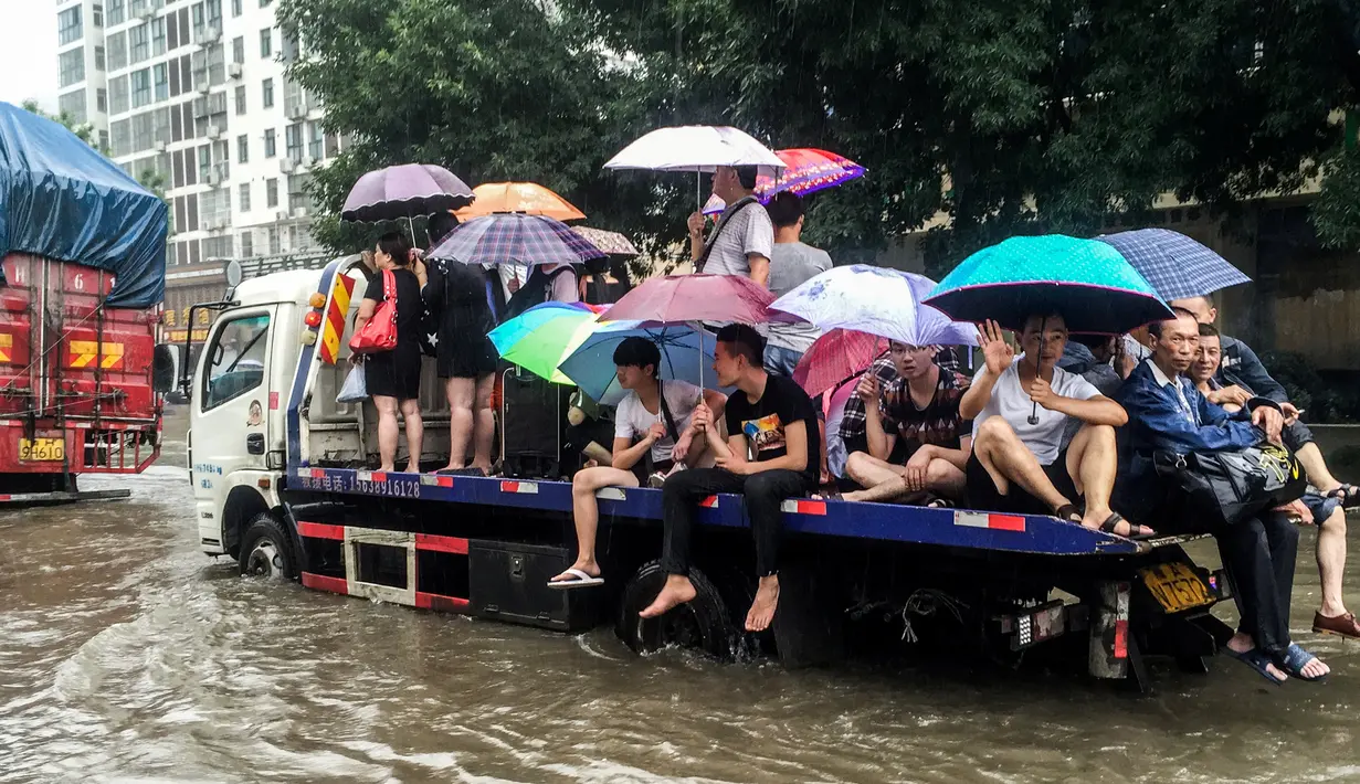 Warga menumpang truk saat banjir melanda Xinxiang, Provinsi Henan, Tiongkok, (9/7). Sedikitnya 420 ribu warga dari 4 kota setempat, termasuk ibukota Fuzhou terpaksa dievakuasi ke tempat yang lebih aman. (REUTERS)