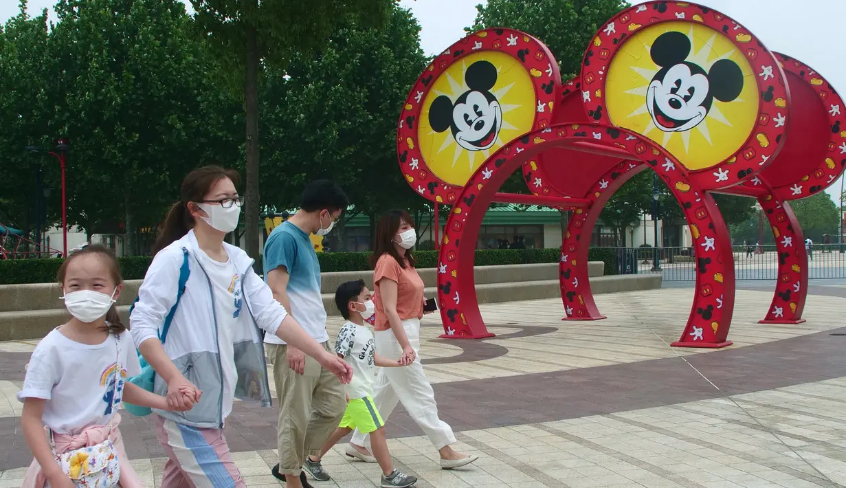 Wisatawan mengenakan masker saat berjalan di taman hiburan Disneyland, Shanghai, China, Senin (11/5/2020). Tiket untuk awal pembukaan kembali Disneyland Shanghai terjual dengan cepat pada Jumat lalu. (AP Photo/Sam McNeil)