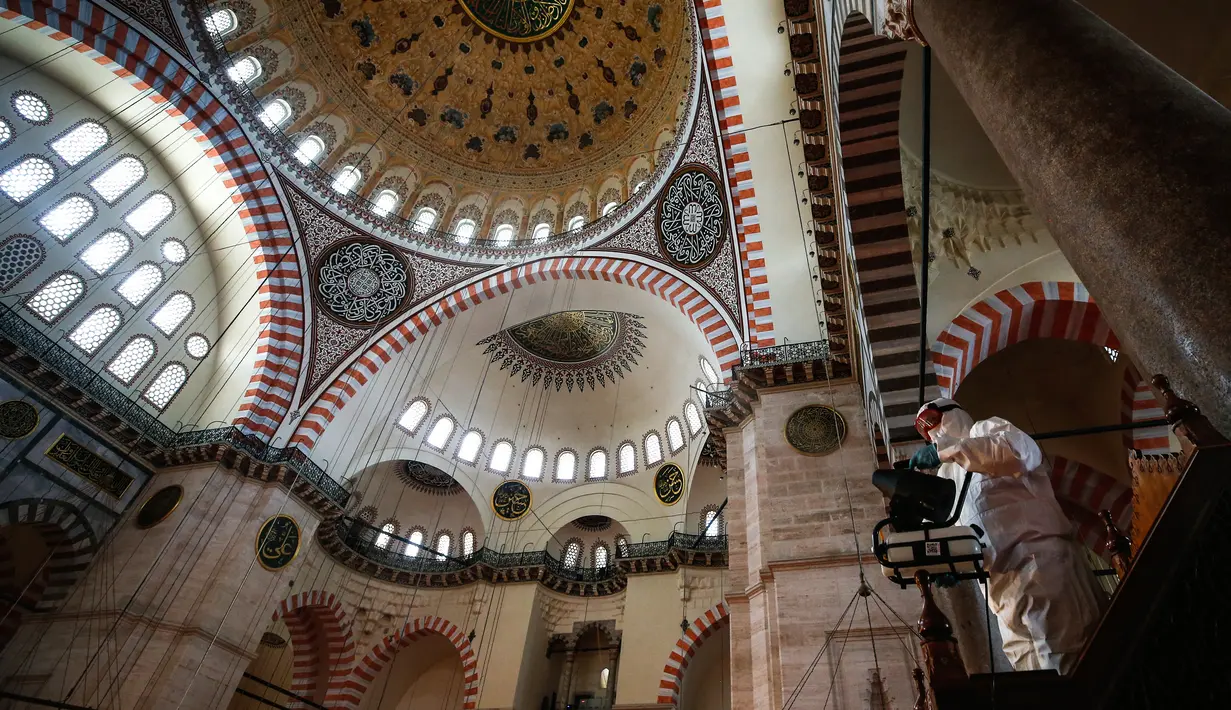 Pekerja mengenakan pakaian pelindung menyemprotkan disinfektan bagian dalam Masjid Suleymaniye yang bersejarah pada hari ketiga Idul Fitri di Istanbul, Selasa (26/5/2020). Beberapa masjid didisinfektan sebelum dibuka kembali pada 29 Mei usai ditutup selama lebih dari enam minggu. (AP/Emrah Gurel)