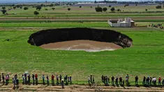 Pemandangan udara dari sinkhole yang ditemukan oleh petani di lahan pertanian di Santa Maria Zacatepec, negara bagian Puebla, Meksiko pada 30 Mei 2021. Lubang yang penuh dengan air itu pada hari Minggu lebarnya hanya sekitar 30 meter. (JOSE CASTAÑARES/AFP)
