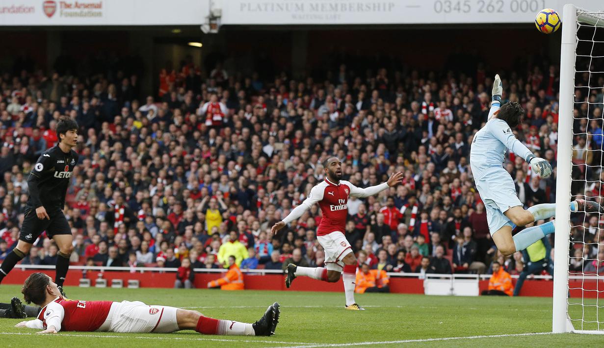Kiper Swansea City, Lukasz Fabianski, berusaha menghalau bola saat pertandingan melawan Arsenal pada laga Premier League di Stadion Emirates, Sabtu (28/10/2017). Arsenal menang 2-1 atas Swansea City. (AP/Frank Augstein)