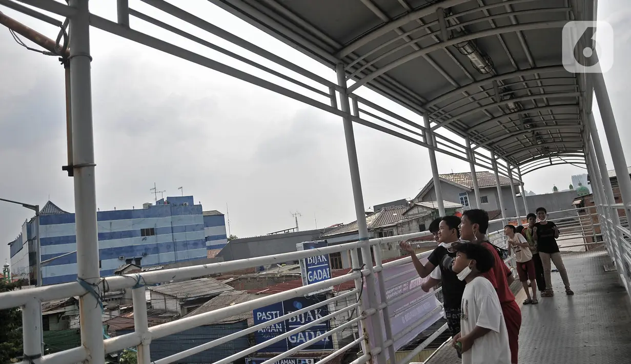 Sejumlah anak menerbangkan layangan dari Jembatan Penyeberangan Orang (JPO) di Jakarta, Kamis (11/6/2020). Minimnya ruang terbuka di sekitar tempat tinggal anak-anak itu menyebabkan mereka terpaksa bermain layang-layang di JPO yang sangat berisiko dan berbahaya. (merdeka.com/Iqbal Nugroho)