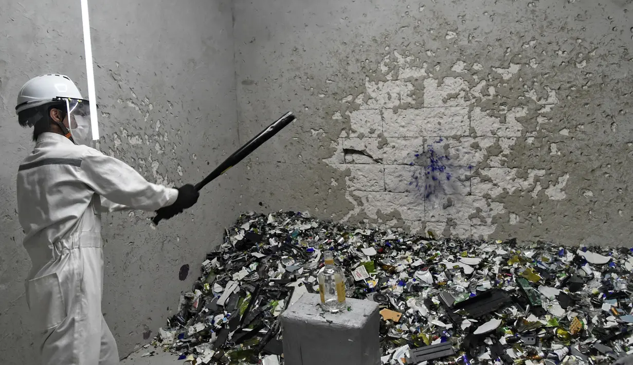 Seorang pria memukul botol di "rage room" atau ruang kemarahan di Singapura (19/10). Tempat ini disediakan untuk para karyawan yang ingin melampiaskan hari buruk mereka dan stres karena tekanan di kantor. (AFP Photo/Roslan Rahman)