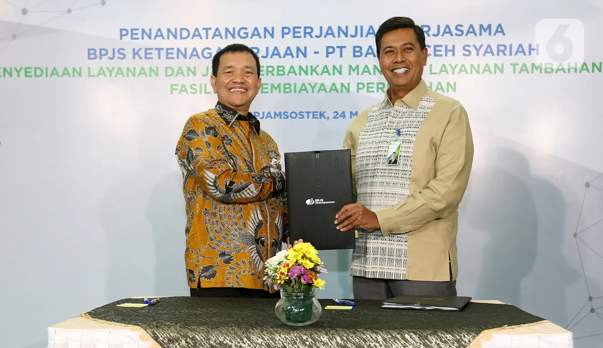 Direktur Utama BPJS Ketenagakerjaan (BPJAMSOSTEK) Anggoro Eko Cahyo (kanan) dan Direktur Utama Bank Aceh Haizir Sulaiman (kiri) menunjukkan naskah Perjanjian Kerja Sama dalam Rangka Pemberian Manfaat Layanan Tambahan (MLT) di Plaza BPJAMSOSTEK Jakarta, Kamis (24/03/2022). (Liputan6.com/Fery Pradolo)