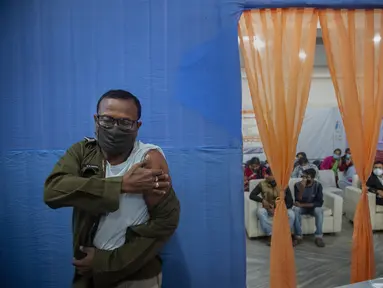 Petugas polisi menekan lengannya setelah menerima vaksinasi COVID-19 dosis ketiga di rumah sakit pemerintah di Gauhati, India (10/1/2022). India pada Senin (10/1) mulai memberikan dosis penguat (booster) vaksin COVID-19 bagi pekerja di lini depan dan lansia yang rentan.  (AP Photo/Anupam Nath)