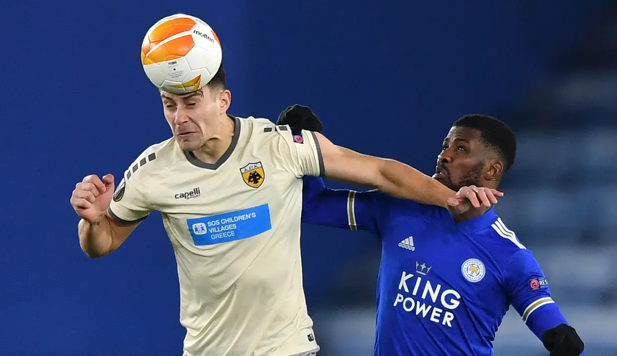 Bek AEK Athens, Ionut Nedelcearu (kiri), berduel udara dengan striker Leicester City, Kelechi Iheanacho, dalam laga lanjutan Liga Europa 2020/21 Grup G di King Power Stadium, Kamis (10/12/2020). AEK Athens kalah 0-2 dari Leicester City. (AFP/Ben Stansall)