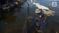 Akivitas warga saat terjadinya banjir rob di Pelabuhan Kali Adem, Muara Angke Jakarta, Rabu (5/1/2022). Menurut BMKG, adanya fase bulan baru yang bersamaan dengan masa Perigee (jarak terdekat bulan bumi) menyebabkan peningkatan signifikan ketinggian pasang air laut. (merdeka.com/Imam Buhori)
