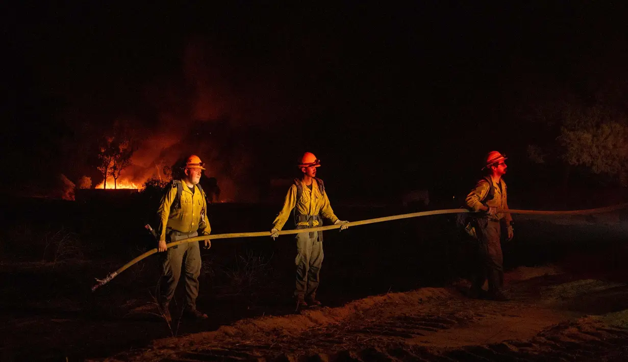 Petugas pemadam kebakaran memegang selang air saat memadamkan kebakaran hutan yang disebut Highland Fire di Aguanga, California, Senin, 30 Oktober 2023. (AP Photo/Ethan Swope)