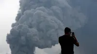 Seorang wisatawan mengabadikan gambar semburan abu vulkanik dari Gunung Bromo yang sedang erupsi di Ngadisari, Probolinggo, Jawa Timur, Selasa (5/1/2016). (REUTERS/Darren Whiteside)