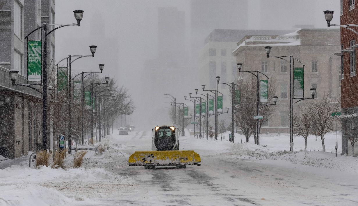 Sebuah traktor salju melaju di jalan kosong di lingkungan East Village, Des Moines, Iowa, pada tanggal 12 Januari 2024. (Christian MONTERROSA/AFP)