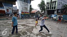 Seorang remaja saat mengiring bola saat bermain di kolong rel kereta kawasan Juanda, Jakarta, Jumat (27/5). Tidak tersedianya ruang terbuka menyebabkan lahan tersebut dijadikan tempat bersosialisasi bagi warga. (Liputan6.com/Immanuel Antonius)