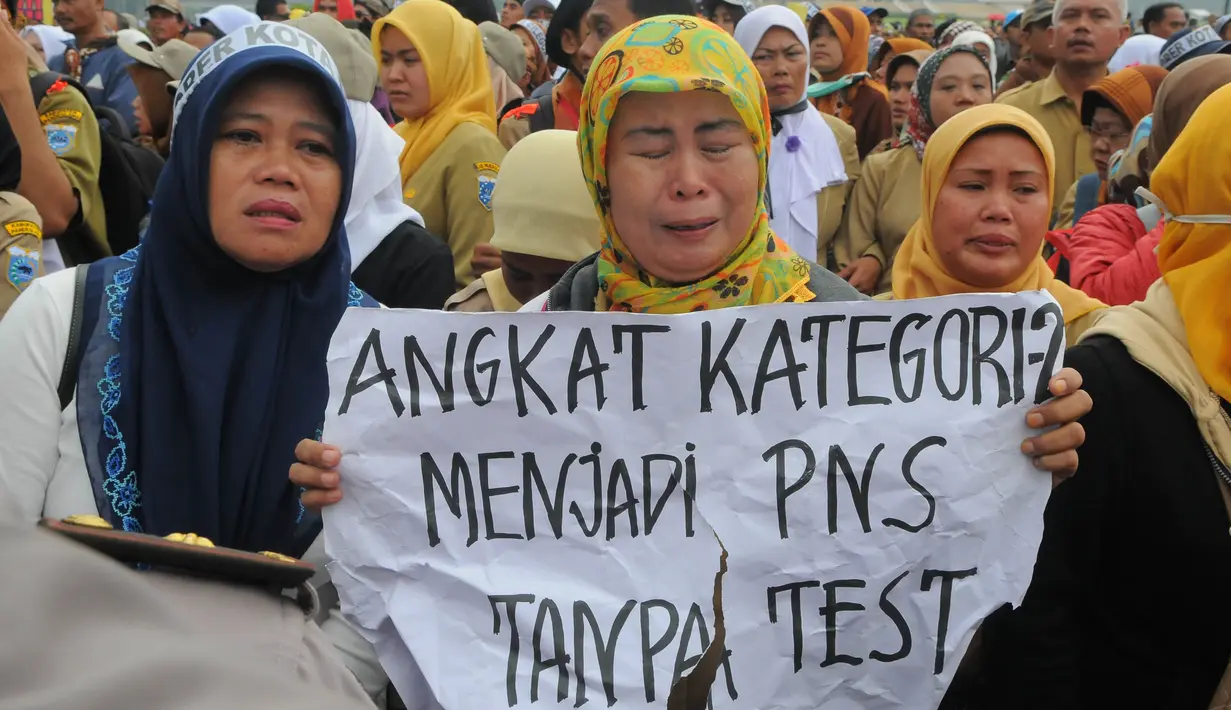 Seorang pengunjuk rasa tampak menangis sambil memegang sebuah karton yang bertuliskan `Angkat Kategori 2 Menjadi PNS Tanpa Test` (Liputan6.com/Herman Zakharia).