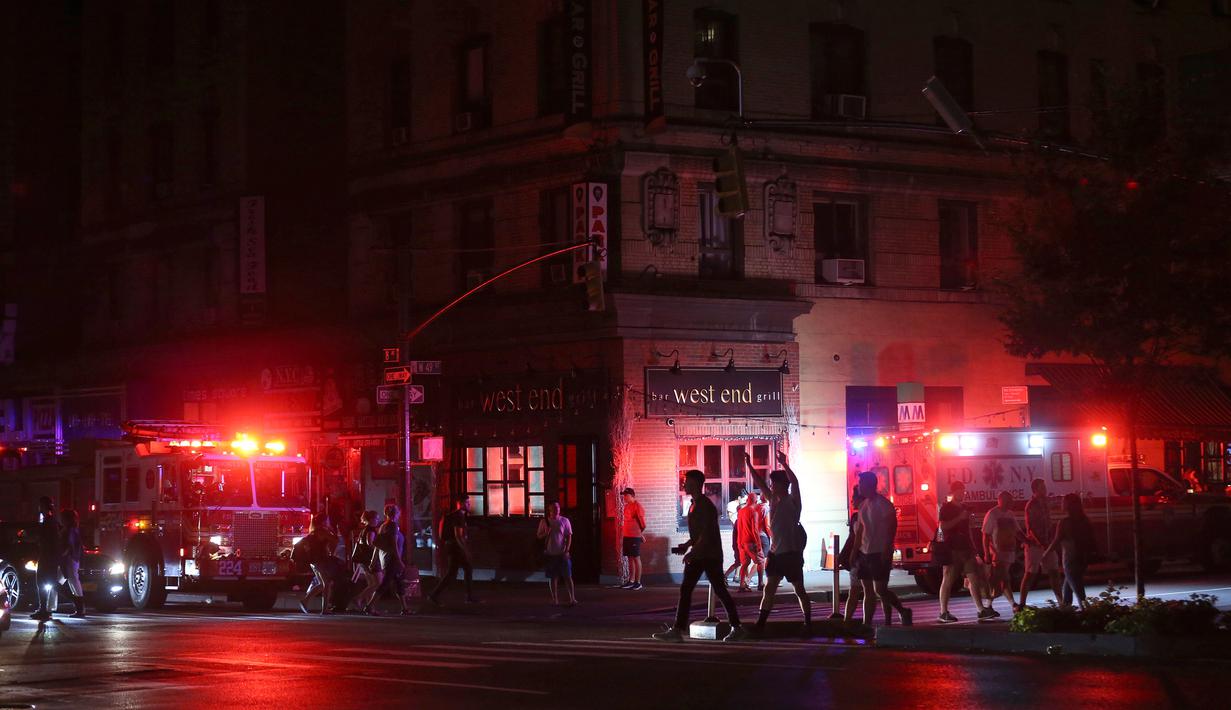Pejalan kaki menyeberang jalan dekat kendaraan tanggap darurat saat pemadaman listrik di New York, AS, Sabtu (13/7/2019). Pemadaman listrik melanda sekitar 42 ribu pelanggan di Kota New York. (AP Photo/Michael Owens)