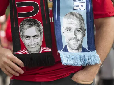 Seorang fans mengenakan slayer bergambar pelatih Manchester City,  Pep Guardiola (kanan) dan pelatih  Manchester United, Jose Mourinho,  pada laga Premier League di Old Trafford, Manchester,  (10/9/2016). (AFP/Oli Scarff)