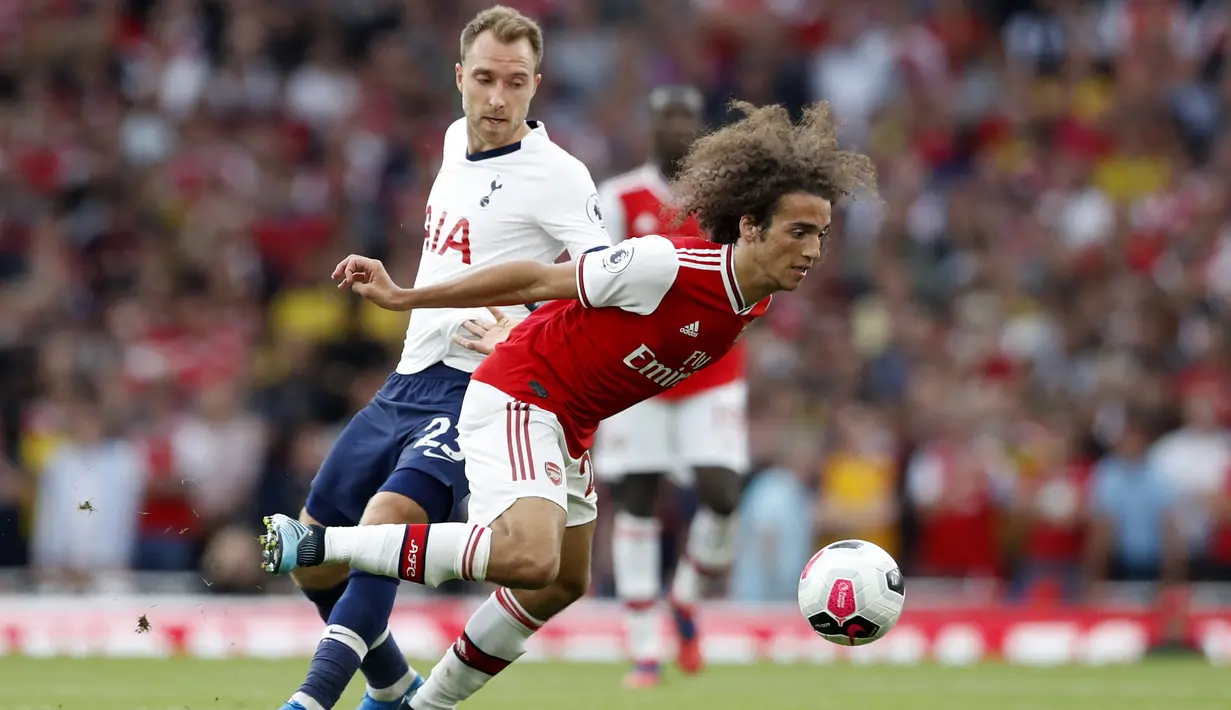 Gelandang Arsenal, Matteo Guendouzi melewati gelandang Tottenham Hotspur, Christian Eriksen selama pertandingan Liga Inggris di stadion Emirates di London (1/9/2019). Arsenal bermain imbang 2-2 atas Tottenham. (AP Photo/Alastair Grant)