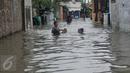 Warga menuntun anaknya melewati banjir yang mencapai pinggang orang dewasa di Rawa Buaya, Jakarta, Minggu (28/2/2016). Banjir terjadi akibat luapan Kali Mookervart yang diguyur hujan sejak malam. (Liputan6.com/Gempur M Surya)