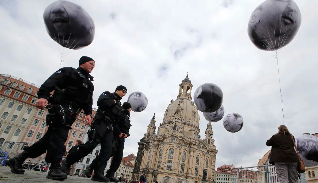 Sejumlah petugas berjalan dibawah balon bergambar muka para pemimpin negara G7 yang dibuat oleh kelompok ONE, Dresden, Jerman, (27/5/2015). Dresden menjadi tuan rumah pertemuan menteri keuangan dan gubernur bank sentral G7. (REUTERS/Fabrizio Bensch)