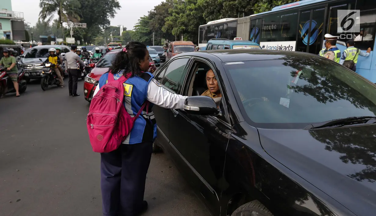 Petugas Dinas Perhubungan membagikan selebaran sosialisasi pemberlakuan sistem ganjil genap di pintu masuk Gardu Tol Cibubur 2, Jakarta, Senin (16/4). Aturan ini diujicobakan di Gerbang Tol pada  Senin 16 April 2018. (Liputan6.com/Faizal Fanani)