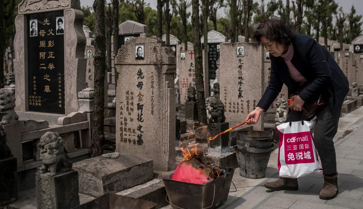 Seorang wanita membakar dupa sebagai persembahan selama festival Qingming di sebuah pemakaman di Shanghai (6/6). Qingming adalah ritual tahunan etnis Tionghoa untuk bersembahyang dan ziarah kubur sesuai dengan ajaran Khong Hu Cu. (AFP/Johannes Eisele)