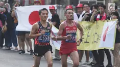 Pelari maraton Jepang, Hiroto Inoue bersaing dengan Elhassan Elabbassi dari Bahrain saat memasuki garis finis lomba Asian Games 2018 di jalan Sudirman, Jakarta, Sabtu (25/8). Hiroto menjadi pemenang lari maraton 42 kilometer. (Merdeka.com/Imam Buhori)