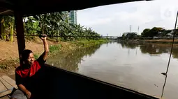 Romli, pemilik perahu eretan duduk menunggu warga menyeberangi Banjir Kanal Barat, Jatipulo, Jakarta, Senin (31/01/2022). Keberadaan perahu eretan sepi penumpang sejak dibangunnya jembatan penyeberangan dan ramainya moda transportasi. (Liputan6.com/Fery Pradolo)