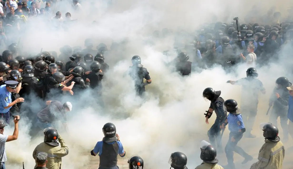 Demonstran menyerang polisi dengan bom asap dan granat gas air mata di depan gedung Parlemen Ukraina , Senin (31/8). Satu petugas tewas dan 90 lainnya terluka dalam aksi yang menentang perubahan UU dasar mengenai desentralisasi. (AFP PHOTO/Genya SAVILOV)