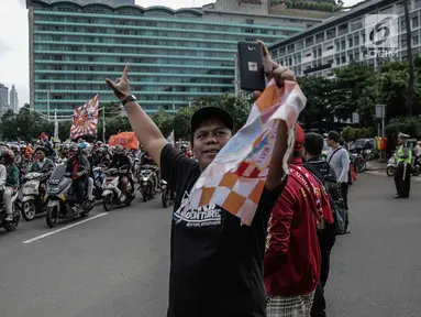 Warga berswafoto dengan latar belakang suporter Persija Jakarta, Jakmania, yang melakukan pawai kemenangan Juara Piala Presiden di kawasan Bundaran HI, Minggu (18/2). Lautan oranye memenuhi jalan-jalan di ibu kota. (Liputan6.com/Faizal Fanani)