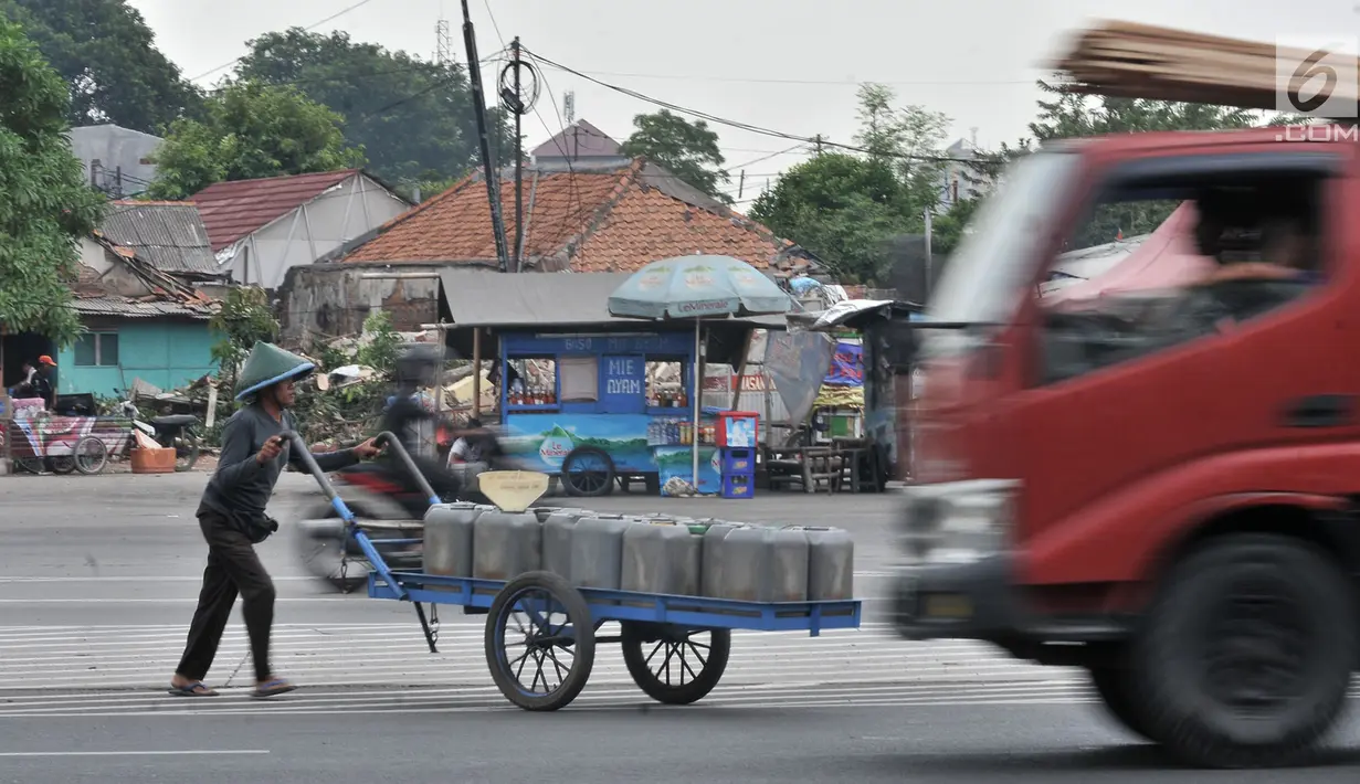 Pedagang air bersih saat dengan hati-hati menyeberangi jalan di persimpangan Terminal Pulo Gadung, Jakarta, Rabu (5/9). Menurut warga setempat, kecelakaan hampir setiap hari terjadi di persimpangan ini. (Merdeka.com/Iqbal Nugroho)