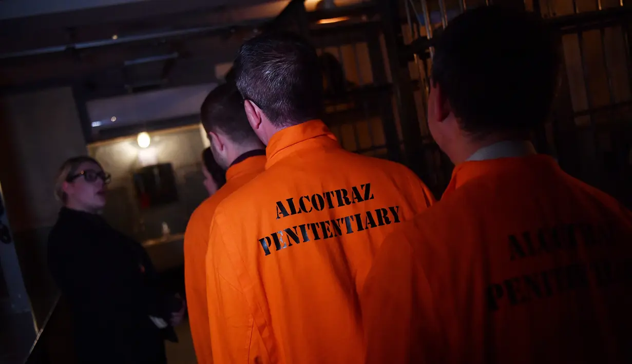 Para pengunjung mengenakan baju tahanan berwarna oranya saat memasuki bar koktail Alcotraz  di London , 11 Oktober 2018. Pengunjung harus mengganti pakaian mereka dengan baju tahanan untuk memasuki bar berkonsep penjara ini. (BEN STANSALL / AFP)