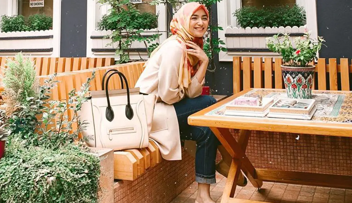 Wanita kelahiran 23 April 1994 ini selalu tampil dengan outfit yang simple salah satunya saat ia memakai hijab berwarna oranye dengan corak merah dipadu atasan berwarna krem dan celana jeans. (Liputan6.com/IG/@citraciki)