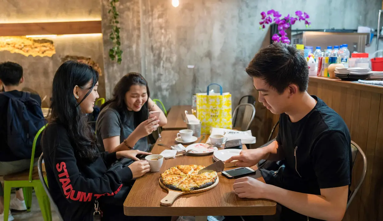 Pengunjung memotong pizza rasa durian di kafe Mao Shan Wang di Singapura (26/1). Restoran yang menyediakan beragam aneka rasa durian ini telah menarik banyak pengunjung untuk datang mencicipi buah durian di kafe tersebut. (AFP Photo/Nicholas Yeo)