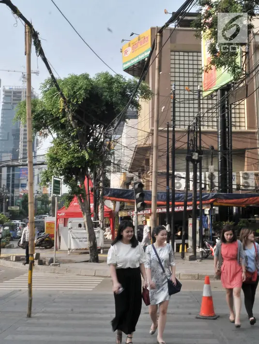 Pejalan kaki melintasi bambu penyangga kabel di Jalan Wahid Hasyim, Jakarta, Selasa (6/11).  Dua buah bambu penyangga kabel menjuntai yang sudah ada sejak beberapa hari lalu tersebut berada di tengah jalan. (Merdeka.com/Iqbal S. Nugroho)