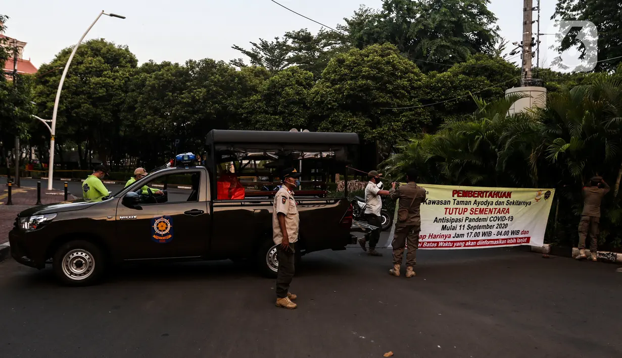 Petugas menutup area kawasan Taman Ayodya, Jalan Bulungan dan Mahakam, Jakarta, Rabu (23/9/2020). Penutupan jalan dilakukan agar masyarakat tidak berkumpul di area tersebut pada waktu malam hari dan guna menekan angka penularan virus corona COVID-19. (Liputan6.com/Johan Tallo)