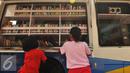 Sejumlah anak membaca buku di mobil perpustakaan keliling di halaman Rusun Cipinang Besar Selatan, Jakarta, Rabu (27/4). Pemprov DKI Jakarta melengkapi fasilitas rusun tersebut berupa perpustakaan dan taman bermain anak. (Liputan6.com/Gempur M Surya)