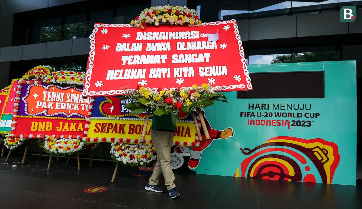 Seorang petugas membawa karangan bunga di kantor PSSI yang terletak di GBK Arena, Senayan, Jakarta, Kamis (30/03/2023) sebagai respon pembatalan Indonesia sebagai tuan rumah Piala Dunia U-20 2023 oleh FIFA. (Bola.com/Bagaskara Lazuardi)