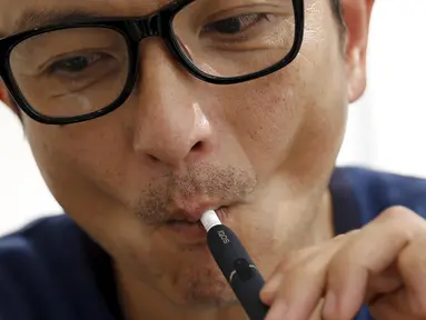 Salah satu pelanggan saat mencoba iQOS di sebuah toko, Tokyo , Jepang , (3/3).  iQOS merupakan sebuah alat pemanas untuk sebatang rokok dengan menggunakan listrik. (REUTERS / Toru Hanai)