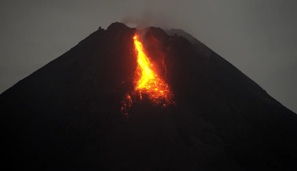 Gunung Merapi mengeluarkan lava pijar yang teramati dari Yogyakarta (7/1/2021).  Jarak luncur maksimumnya 800 meter ke arah kali Krasak. (AFP/Agung Supriyanto)