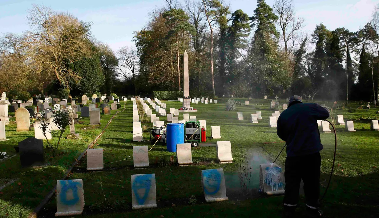 Pekerja membersihkan batu nisan kuburan Harefield di Hillingdon, Inggris, Rabu (23/11). Kuburan prajurit Australia & New Zealand yang tewas pada Perang Dunia I dicoret dengan graffiti kedua kalinya dalam 7 bulan terakhir di London.(REUTERS/Stefan Wermuth)
