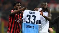 Dua gelandang AC Milan, Franck Kessie dan Tiemoue Bakayoko, mengarak jersey milik Francesco Acerbi selepas duel melawan Lazio di San Siro, Sabtu (13/4/2019). (AFP/Miguel Medina)