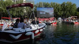 Orang-orang menghadiri pemutaran film "Le grand bain" pada hari pertama acara musim panas "Paris-Plages" di La villette bassin, Paris, 18 Juli 2020. Paris menghadirkan sebuah terobosan baru dengan bioskop terapung lengkap dengan perahu yang tetap menjaga jarak sosial. (GEOFFROY VAN DER HASSELT/AFP)