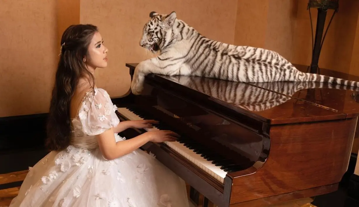 Tiara Andini bahkan ikut pemotretan bareng Alshad Ahmad dan harimau peliharaannya. Penyanyi berusia 21 tahun itu tampil cantik bak seorang putri yang duduk di depan piano. Sementara, Selen si macan putih peliharaan kesayangan Alshad tampak duduk tenang di atas piano tersebut. (Liputan6.com/IG/@tiaraandini)