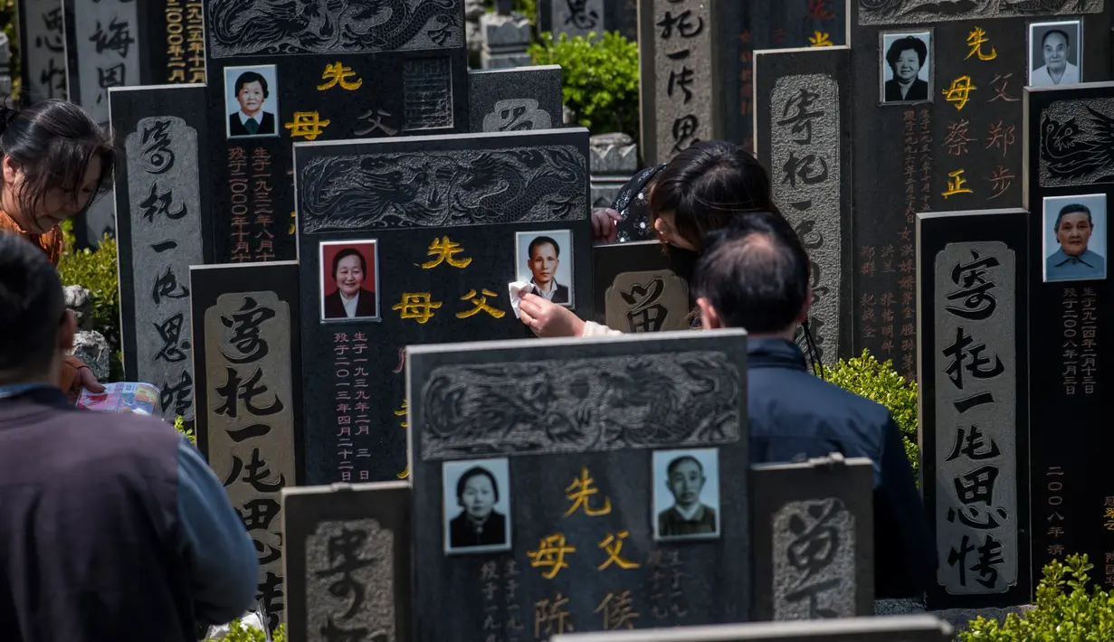 Peziarah membersihkan batu nisan keluarga mereka untuk menyambut festival Ching Ming dikomplek pemakaman di Shanghai (3/4). Mereka berdoa di depan nenek moyang, menyapu pusara dan bersembahyang. (AFP/Johannes Eisele)