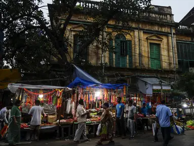 Warga melewati kios pinggir jalan yang menjual perlengkapan ibadah menjelang festival Hindu Chhath, di Kolkata, India  (9/11/2021). Selama Chhath, festival Hindu kuno yang populer di kalangan kelas pekerja, ritual dilakukan untuk berterima kasih kepada Dewa Matahari. (AP Photo/Bikas Das)