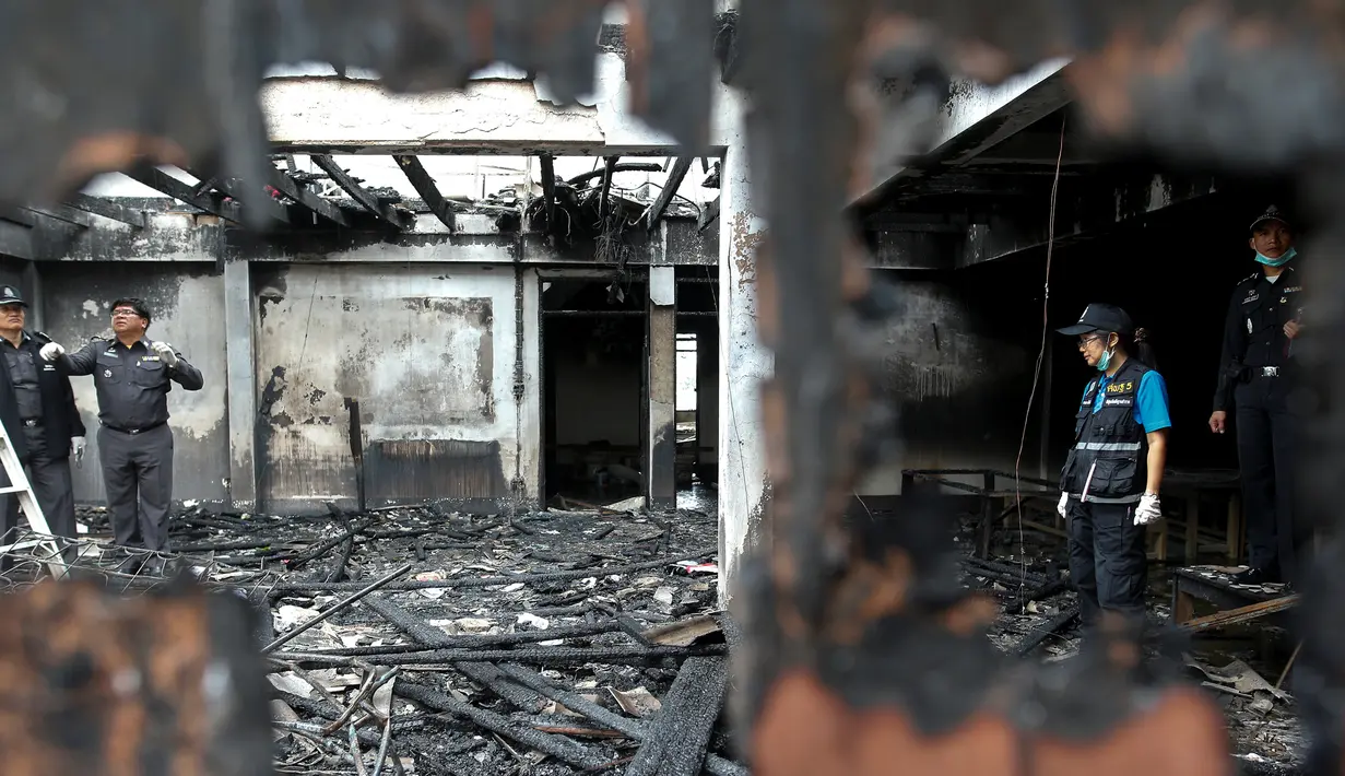 Ahli forensik memeriksa bangunan asrama sekolah khusus anak perempuan dari keluarga suku pedalaman miskin yang terbakar di Thailand utara, Senin (23/5). Setidaknya 17 anak perempuan tewas dalam kebakaran tersebut. (REUTERS/Athit Perawongmetha)
