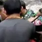Warga dan personel TNI bersama-sama menggotong Muriamah dan bayi yang ada dalam kandungan.