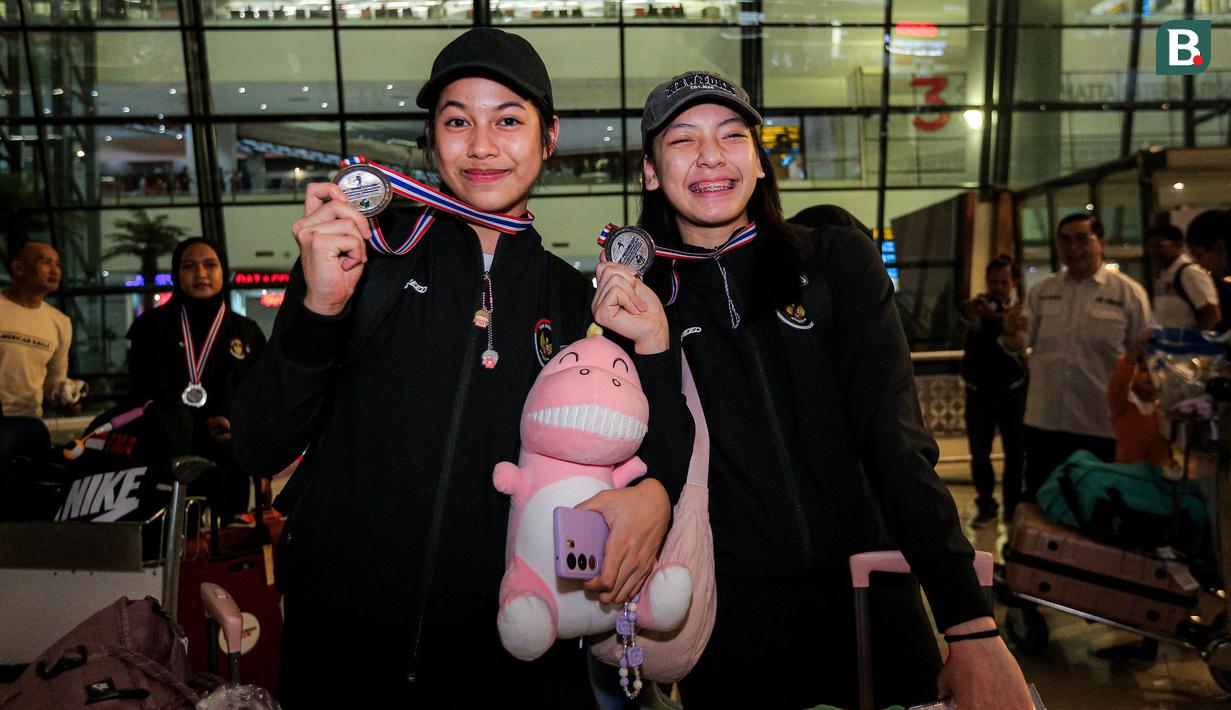 <p>Dua pemain Timnas voli putri Indonesia U-18, Poppy Aulia Nursutan (kiri) dan Venisa Dwi Oktani berpose dengan medali perak turnamen bola voli putri Princess Cup 2024 dalam acara penyambutan di Terminal 3 Bandara Soekarno Hatta, Tangerang, Jumat (14/6/2024). (Bola.com/Bagaskara Lazuardi)</p>