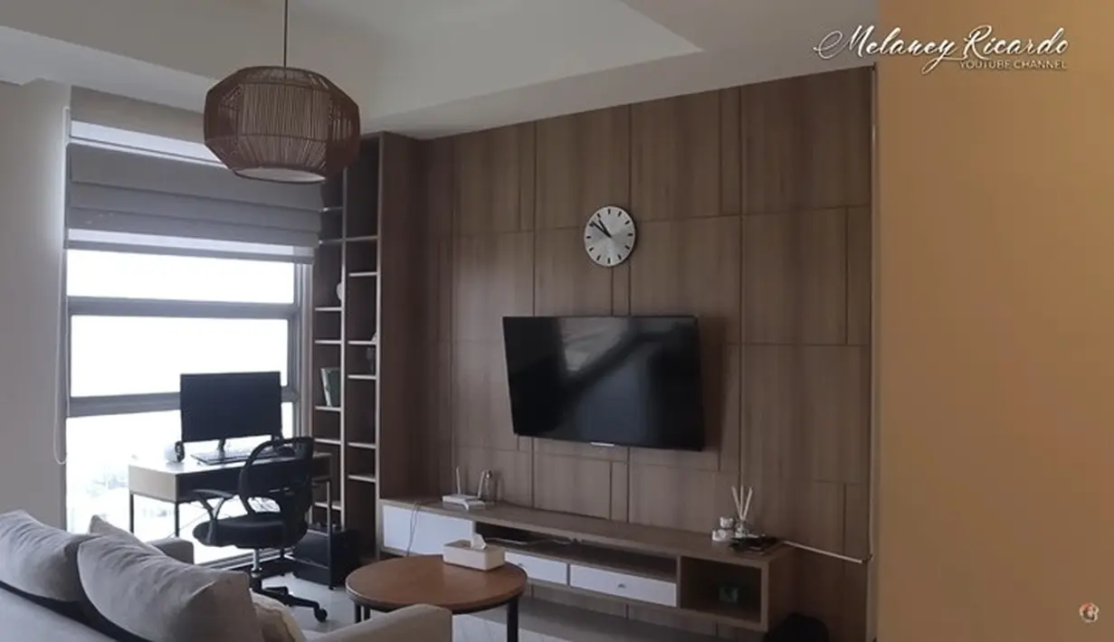 Tampak meja komputer dan televisi yang biasa digunakan untuk hiburan hingga menonton Youtube. Di depan sofa ada meja bundar ukuran kecil. Sofa muat dua orang dan meja bundar di depan ruang teve. Menurutnya, dirasa cukup untuk dirinya yang tinggal sendiri. [Youtube/Melaney Ricardo]